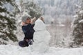 Little girl sculpts snowman in winter snowy Park. Game. Royalty Free Stock Photo