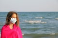 Little girl by the sea with a bathrobe and surgical mask to prot Royalty Free Stock Photo