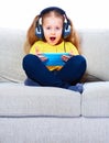 Little girl seating on sofa using tablet pc.