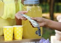 Little girl selling natural lemonade to African-American boy in park. Summer refreshing drink Royalty Free Stock Photo