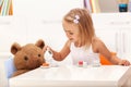 Little girl serving tea to her toy bear Royalty Free Stock Photo