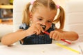 Little girl sharpens a pencil.