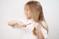 little girl shears her long hair with scissors and afraid on a white background. Royalty Free Stock Photo
