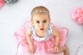 A little girl in a shiny party dress looks up. Cute baby`s face close-up.