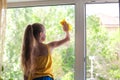 Little girl in shirt and blue shorts washes the windows at home. Daughter with a cat wash the window Royalty Free Stock Photo