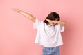 Little girl showing dab dance pose, famous internet meme of triumph, performing dabbing trends.