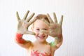 Little girl showing her hands, covered in finger paint