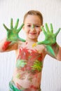 Little girl showing her hands, covered in finger paint