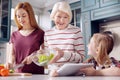 Little girl showing salad recipe to her mother and grandmother Royalty Free Stock Photo