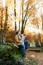 Little girl shows her dad to a tree while sitting on his knees on a stump in an autumn park Royalty Free Stock Photo