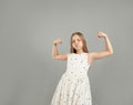 A little girl shows her strength. A beautiful young girl demonstrating the strength of her arms poses in a light light