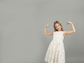 A little girl shows her strength. A beautiful young girl demonstrating the strength of her arms poses in a light light