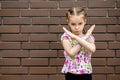 A little girl shows a stop gesture with her arms crossed in front of her