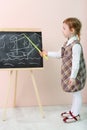 Little girl shows by yellow pointer ship at chalkboard