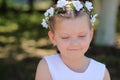 Little girl is shy and looks down, a child with a wreath of artificial flowers on her head Royalty Free Stock Photo