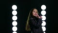 Little girl singing in front of stage lights