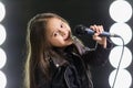 Little girl singing in front of stage lights