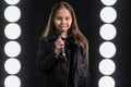 Little girl singing in front of stage lights