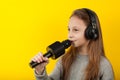 Little girl sings into a microphone on a yellow background. Karaoke for children Royalty Free Stock Photo