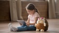 Little girl sit with hedgehog toy using tablet at home