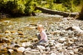 Little girl sit on rocks shore of mountain river