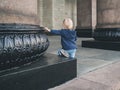 A little girl sits at the base of a massive granite column with her hand resting on her. A monumental building in Moscow Royalty Free Stock Photo