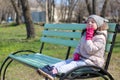 Little girl sits on a bench in the park and smiles hiding behind her hand Royalty Free Stock Photo