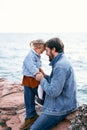 Little girl sits on daddy& x27;s feet, bowing her forehead to his forehead. Daddy sits on stones against the background of Royalty Free Stock Photo