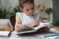 Little girl sits at the desl at home and does homework, self study of the material, reading book