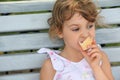 Little girl sits and eats ice-cream