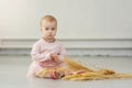A little girl sits on the floor with an armful of wheat ears. One-year-old baby on the floor in an empty room with a Royalty Free Stock Photo