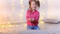 Little girl sits on floor and holds in hands festive confetti.