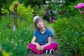 Little girl sits in flowers in the park and dream