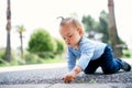 Little girl sits on her knees and picks the asphalt in a green park Royalty Free Stock Photo