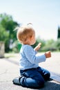 Little girl sits on her knees on the tile. Side view Royalty Free Stock Photo