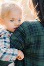 Little girl sits in her mother arms with her chin on her shoulder. Back view. Cropped