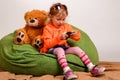 Little girl sits on a high green pillow and plays with mobile ph Royalty Free Stock Photo