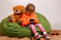 Little girl sits on a high green pillow and plays with mobile ph Royalty Free Stock Photo