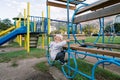 Little girl sits on a ladder with rings in the playground