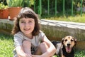 Little girl sits outdoors next to her dog