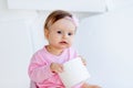 A little girl sits on a potty in pink clothes in a bright room and plays with toilet paper Royalty Free Stock Photo