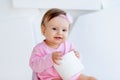 A little girl sits on a potty in pink clothes in a bright room and plays with toilet paper Royalty Free Stock Photo