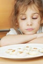 Little girl sits and sadly looks at plate with cookies