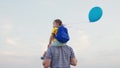 little girl sits shoulders of her dad against sky with balloon. happy family. hold gel ball with hand child kid Royalty Free Stock Photo