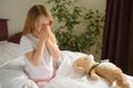 A little girl sits and sneezes on the bed among the blankets and pillows. dust mite allergy Royalty Free Stock Photo