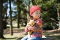 Little girl sitting on a stump with a teddy bear Royalty Free Stock Photo