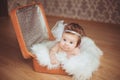 Little girl sits in a suitcase. A dark background.