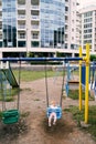 Little girl sits on a swing on a playground in the courtyard of an apartment building Royalty Free Stock Photo