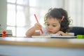Little girl sits at the table and draws on paper with colored pencils, Children education