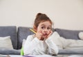 A cute little girl sitting at a table and holding a yellow pen in her hands Royalty Free Stock Photo